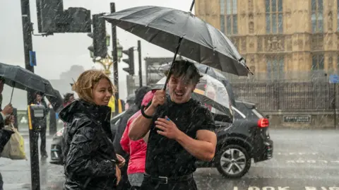 A couple shelter from a heavy downpour in Westminster