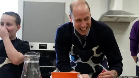 Prince William decorates a biscuit at a youth centre