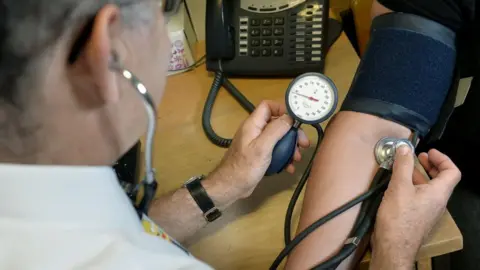 A doctor takes a patient's blood pressure using a stethoscope