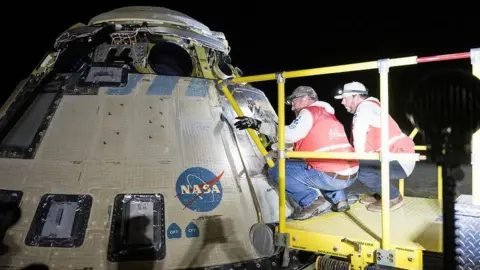 Boeing and NASA teams work around the Starliner spacecraft after it landed on Saturday