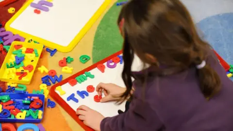 PA Media A child playing with magnetic letters on a whiteboard