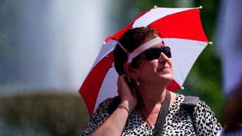 A woman protects her face from the bright sun with a headshield