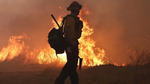 silhouette of a fire fighter against a bush fire