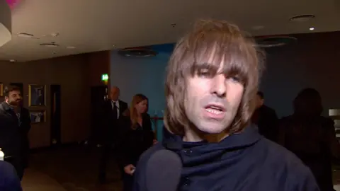 Liam Gallagher talks into a microphone