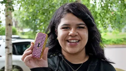 Grace headshot black hair nose ring holding decorated brick phone