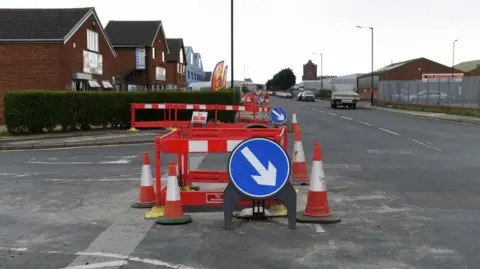 Roadworks signage in the middle of a road junction. There are barriers and cones and a keep right sign. 