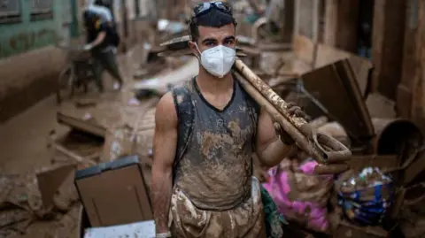 Man cleaning up after flood, wearing face mask