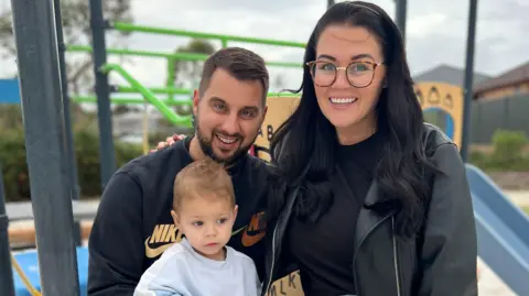 Luca stands in front of his parents, Dante and Laura