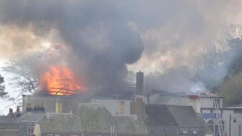 View across rooftops of a large blaze and the sky is filled with smoke