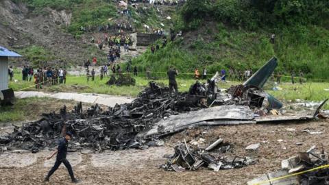 Emergency workers examine the charred wreck of a plane