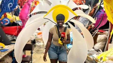 Aminata Kamara smiles at the camera whilst wearing a flowery carnival costume