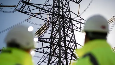 National Grid Two contractors blurred looking up at a pylon