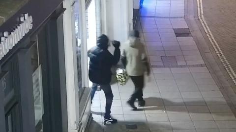 Person throwing an object at a shop window.