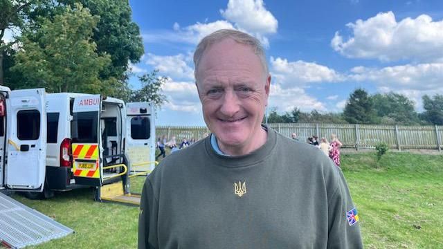 Simon Reevell standing in front of an ambulance at Beswick and Watton School