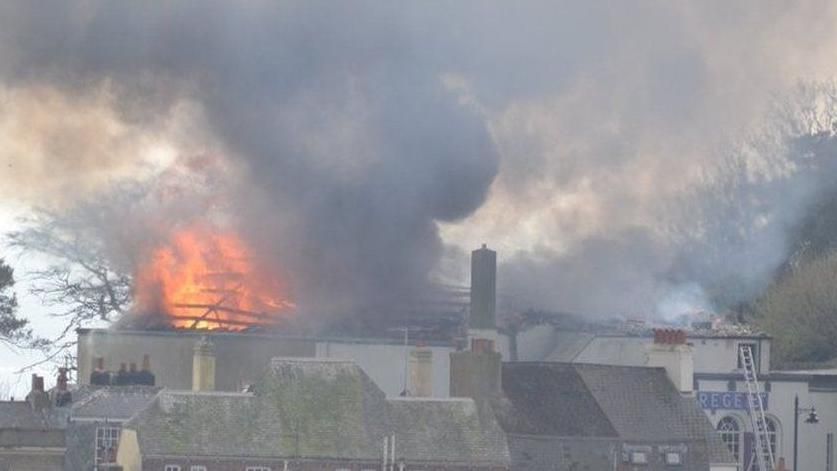 View across rooftops of a large blaze and the sky is filled with smoke