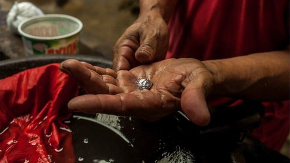 A miner holds a piece of gold in his hand, still chemically bonded to mercury