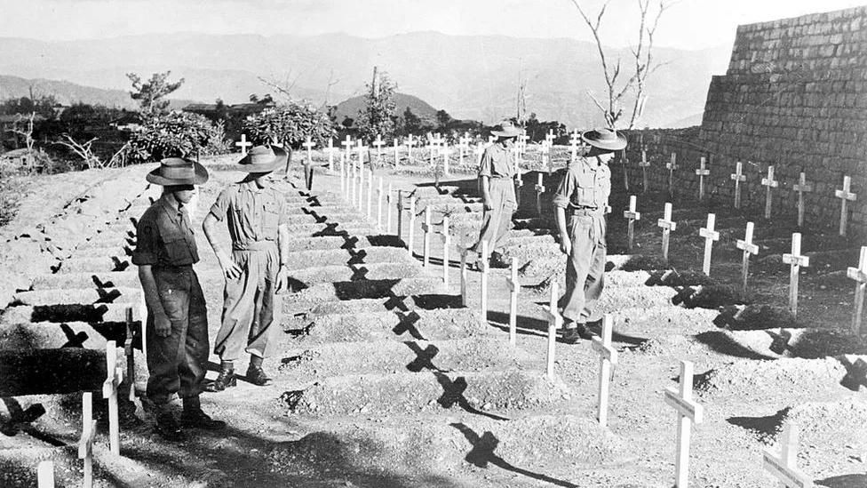 Four soldiers standing amongst rows of crosses