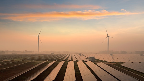 Photo depicts a solar panels and windmills in the power plant