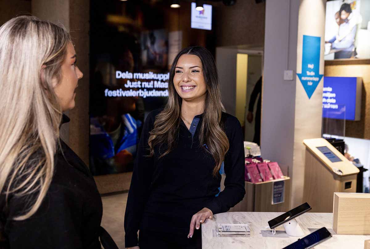 Happy smiling brunette female employee looking at her female blonde co-worker