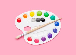 Color palette with paint and brush on pink background