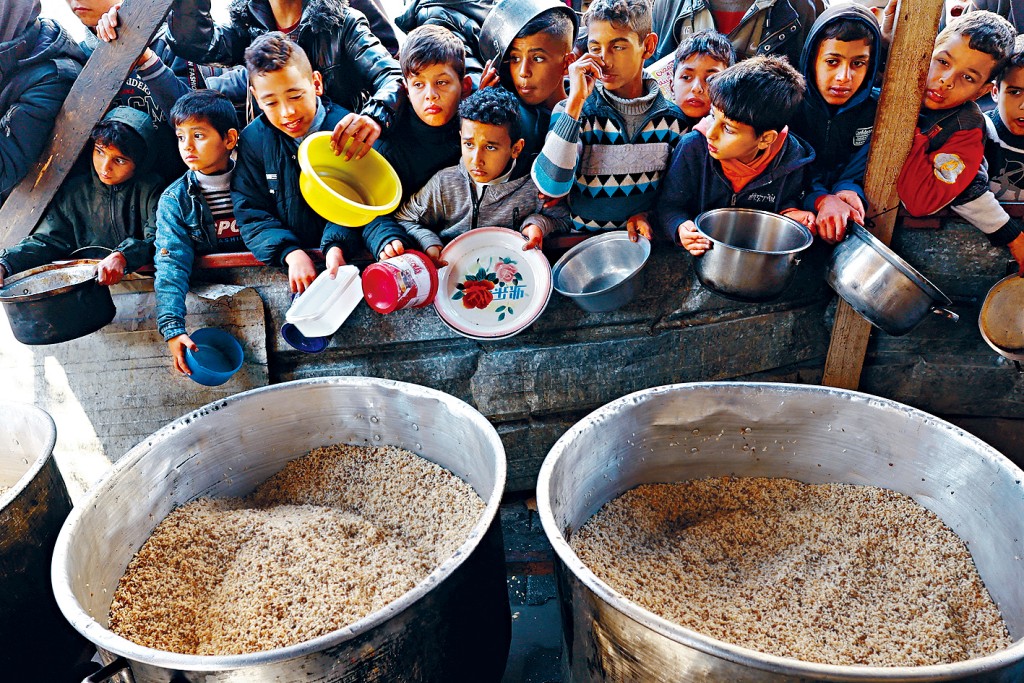 在加沙南部拉法市，大批巴勒斯坦兒童等待領取慈善廚房烹製的食物。