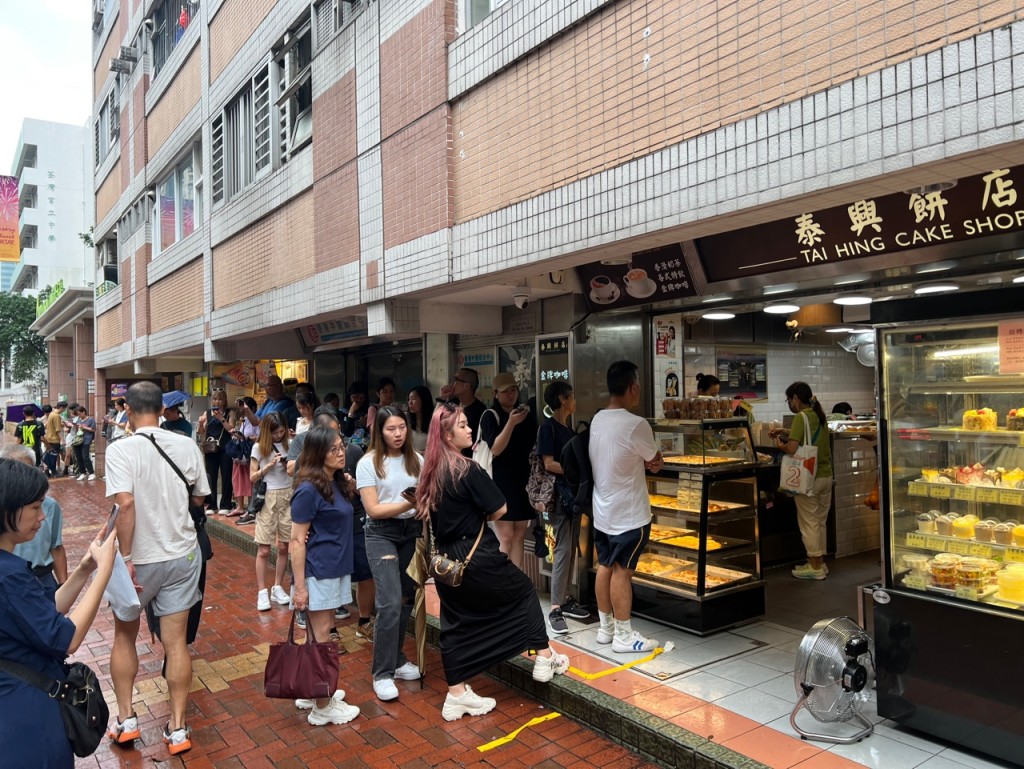 今日间中下起滂沱大雨，下午2时仍有近百人排队购买「热香饼汉堡」。林晓敏摄