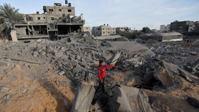 以軍空襲加沙拉法，一名巴勒斯坦青年示意被炸中的房屋。 路透社