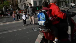 Los padres caminan junto a sus hijos por las desiertas calles de Pekín.