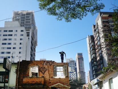 Un trabajador sobre una casa abandonada entre edificios residenciales en São Paulo (Brasil).