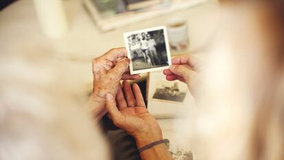 Dos personas observan fotos familiares antiguas.