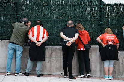 Unos aficionados observan desde una valla las instalaciones del Athletic de Bilbao, el viernes en Lezama (Bizkaia).