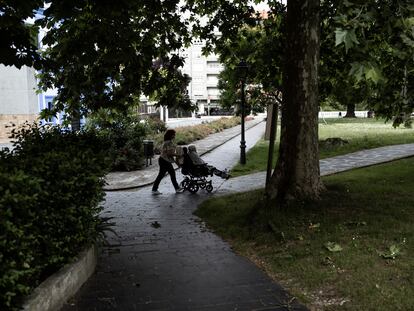 Una mujer empuja a una anciana en silla de ruedas en un parque en Grado, Asturias.