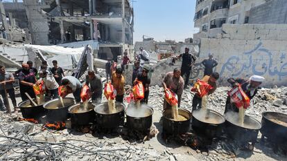 Un grupo de palestinos cocina junto a bloques de viviendas destruidos en Jan Yunis, en el sur de la franja de Gaza, el 30 de mayo de 2024.