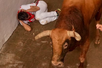 Uno de los mozos se protege en el callejón de entrada a la plaza de toros de Pamplona, este jueves. 