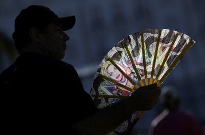 Un hombre se refresca con un abanico decorado con el rostro de Madonna.