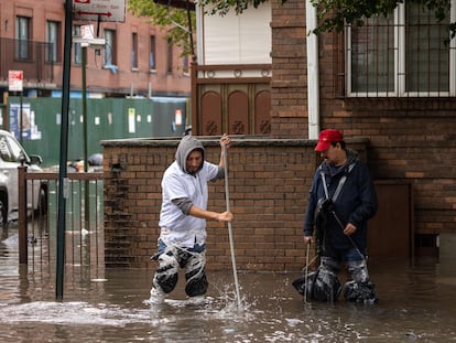 Dos hombres limpian las aguas residuales en una calle inundada durante una fuerte tormenta en Nueva York, el 29 de septiembre de 2023.