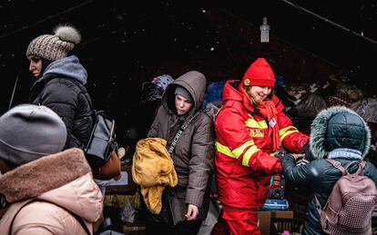 Una trabajadora de los servicios de emergencia rumanos ayuda a los refugiados ucranios en el cruce fronterizo de Siret. Allí algunas imágenes se repiten cada poco: las madres cargando paquetes de pañales, los niños aferrados a su peluche favorito para la travesía, los coches donde se juntan tres generaciones, las ojeras y miradas perdidas como tratando de asimilar algo que está pasando demasiado rápido. Unos pocos coches de gama media-alta y el elegante atuendo con el que algunas ucranias llegan a Rumania recuerda que la fina línea entre una vida desahogada y convertirse en refugiado en un país desconocido es, a veces, una mera cuestión de días.