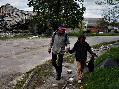 Una pareja camina delante de una vivienda bombardeada en Kupiansk.