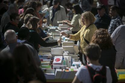 Desenes de persones caminen per la Rambla per Sant Jordi.