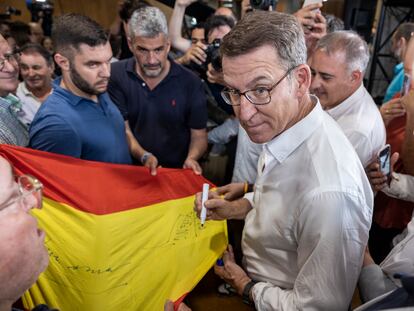 El presidente del PP, Alberto Núñez Feijóo, firma una bandera de España a su llegada al mitin de Murcia el día 12.