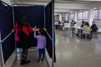 Una mujer junto a su hija dentro de una urna electoral en el Colegio Víctor Jara, La Pintana (Santiago).