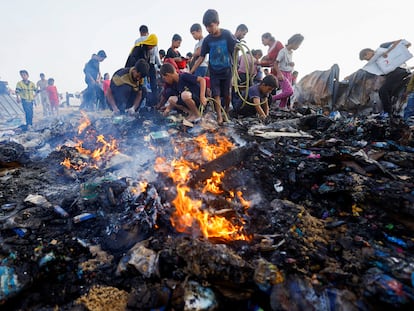 Varios jóvenes buscan comida entre las llamas provocadas por un bombardeo israelí sobre Rafah, en Gaza.