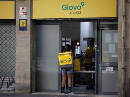 Un rider de Glovo frente a un supermercado express de la compañía de reparto a domicilio en Barcelona, en 2021.