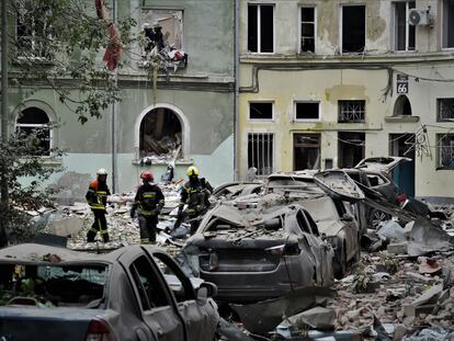 Tres bomberos caminan entre los escombros después de un ataque ruso en la ciudad ucrania de Lviv.