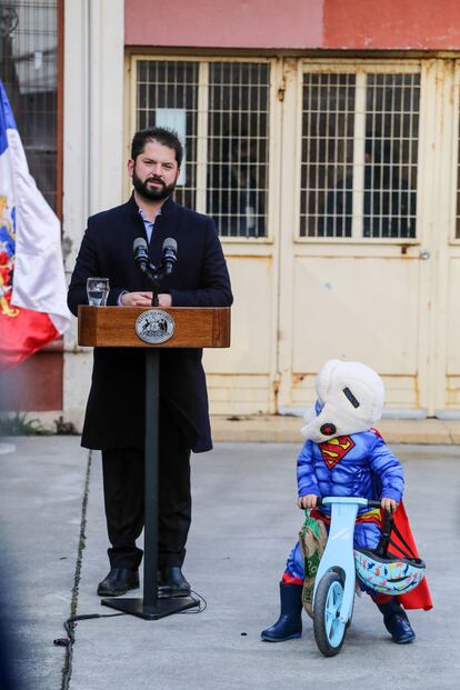 Un niño monta en bicicleta mientras el presidente de Chile, Gabriel Boric, se dirige a la prensa tras votar en Punta Arenas. 
