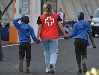 Un efectivo de la Cruz Roja acompaña a dos menores trasladados desde El Hierro, donde habían llegado en cayuco, a Tenerife.