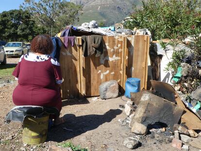Joyce, una mujer que vive en las calles de Ciudad del Cabo, sentada frente al chamizo que habita.