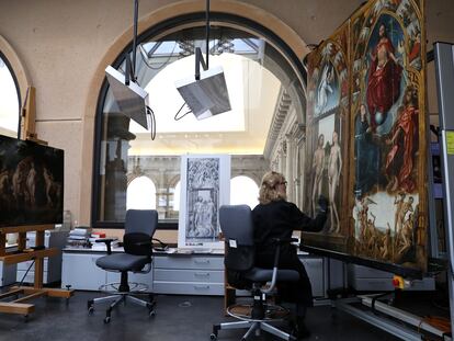 Una mujer trabaja en el taller de restauración del Museo del Prado restaurando las puertas de 'El tríptico de la redención'.