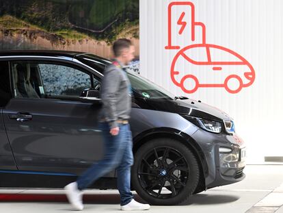 Un empleado de E.ON pasa junto a un coche eléctrico en el centro de electromovilidad que la compañía tiene en Essen (Alemania).