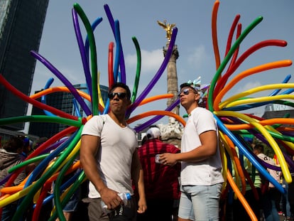 Dos asistentes esperan el inicio de la marcha del orgullo LGBT+ en el Paseo de la Reforma, en Ciudad de México, en junio de 2022.